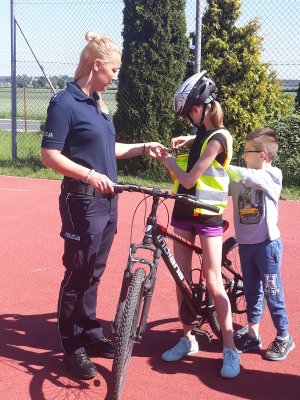 Policjanta przypomina obowiązkowe wyposażenie roweru.