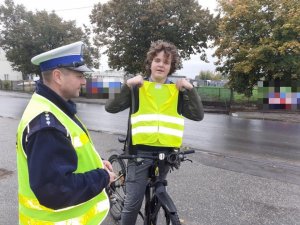 Policjant przekazuje rowerzyście kamizelkę odblaskową