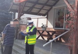 Policjant sprawdza na ulicy czy osoby prawidłowo noszą maseczki