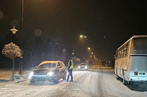 policjant kontroluje na drodze pojazd, pada śnieg, trudne warunki
